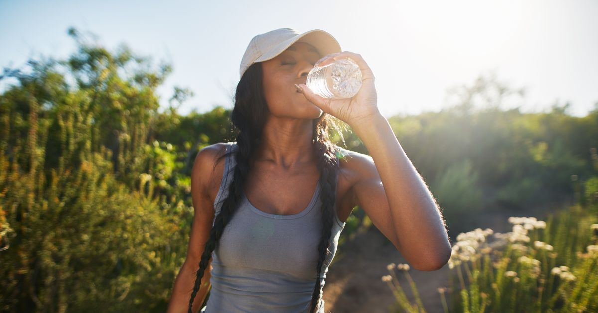 A lady with a hat on drinking a bottle of water