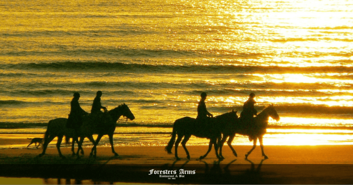 Horseback Riding on the Beach Feature Image- Group of people riding horses during sunset