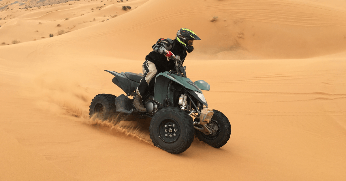 A person riding a quad bike on a sand dune 