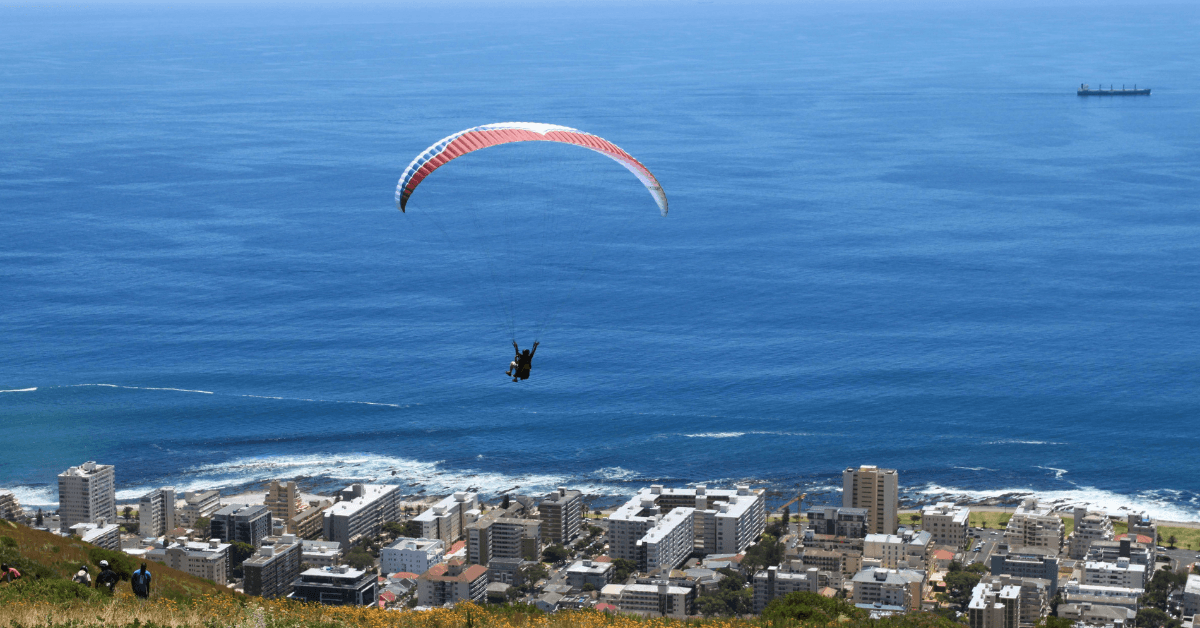 A person paragliding from Signal Hill overlooking the ocean in Cape Town 